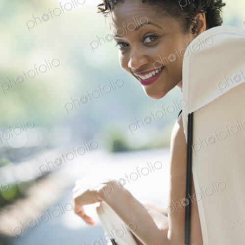 City life. A woman sitting in a camping chair in a city park, smiling and looking over…