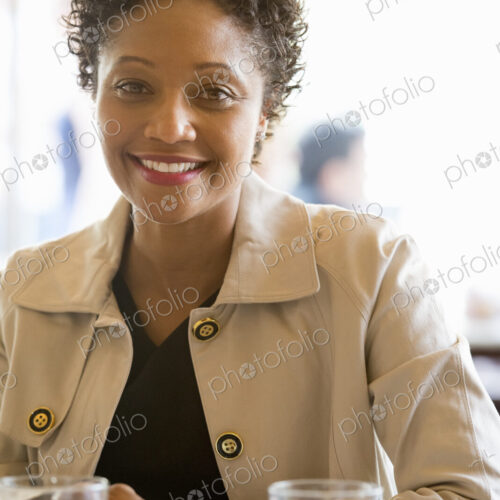 City life. A woman wearing a beige jacket sitting at a table in a cafe City life. A woman wearing a beige jacket sitting at a table in a cafe