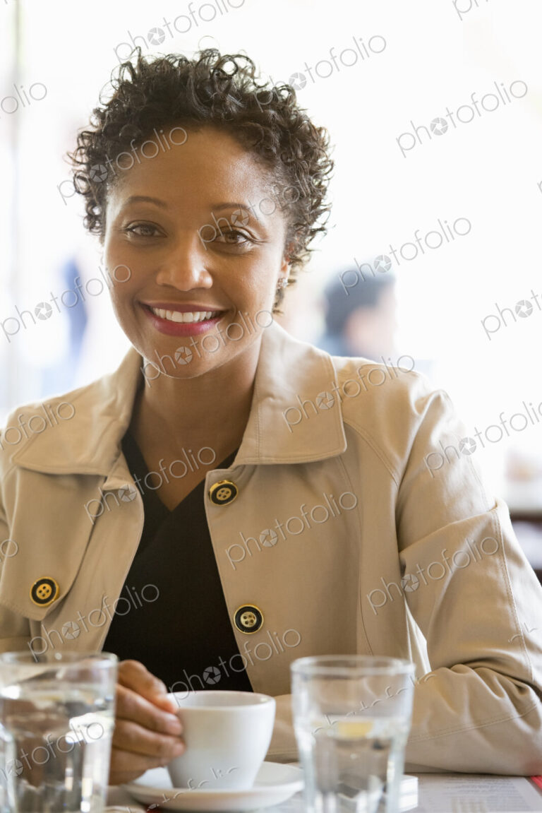 City life. A woman wearing a beige jacket sitting at a table in a cafe