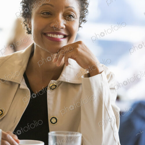 City life. A woman wearing a beige jacket sitting at a table in a cafe City life. A woman wearing a beige jacket sitting at a table in a cafe