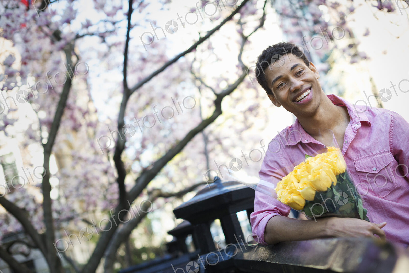 City life. A young man in the park in spring, holding a bunch of yellow roses.