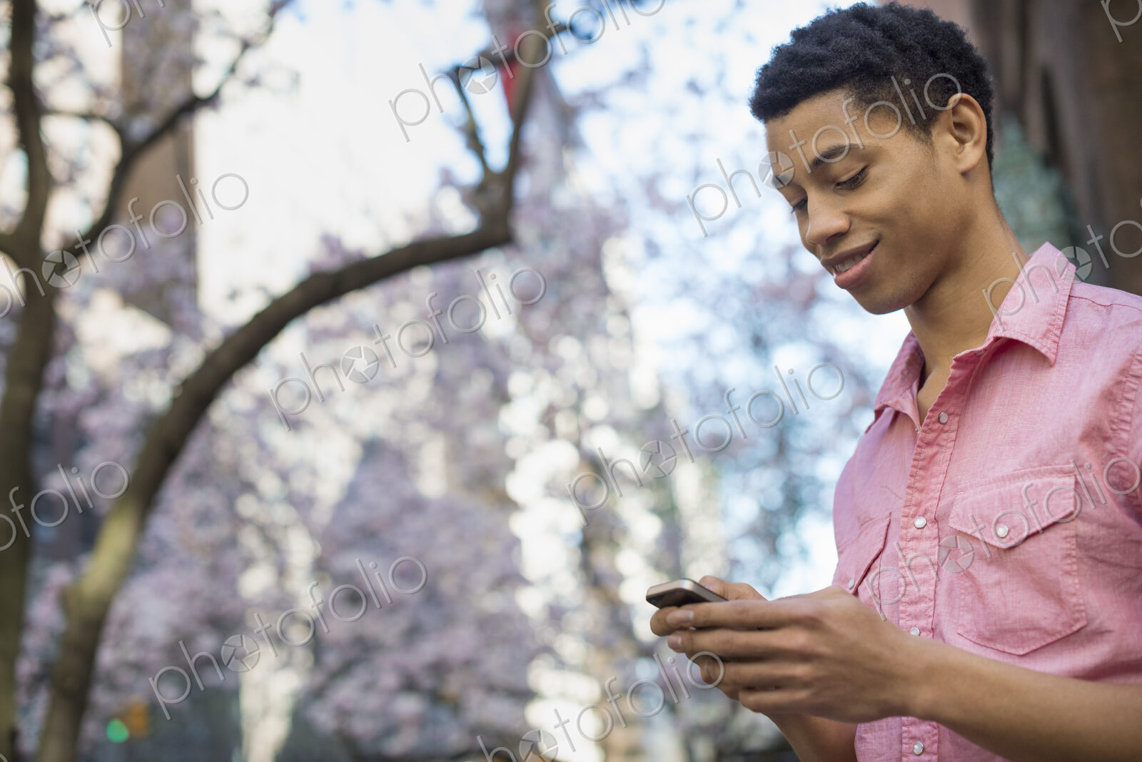 City life. A young man in the park in spring, using a mobile phone.