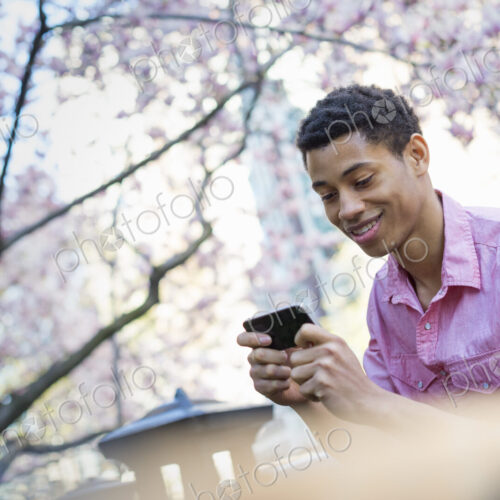 City life. A young man in the park in spring, using a mobile phone.