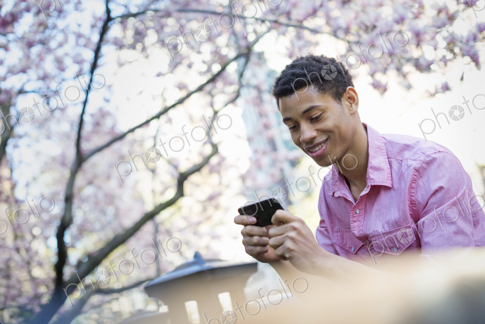 City life. A young man in the park in spring, using a mobile phone.