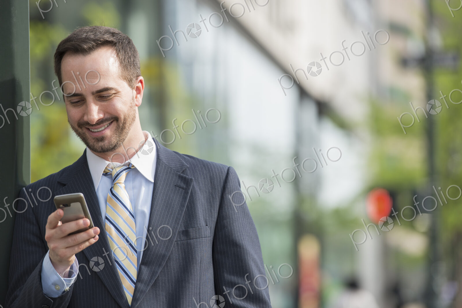 City life. People on the move. A man in a business suit checking his messages on his…