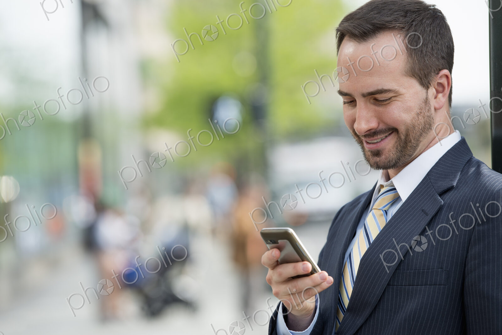 City life. People on the move. A man in a business suit checking his messages on his…