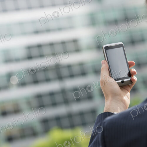 City life. People on the move. A man in a business suit checking his messages on his… City life. People on the move. A man in a business suit checking his messages on his…