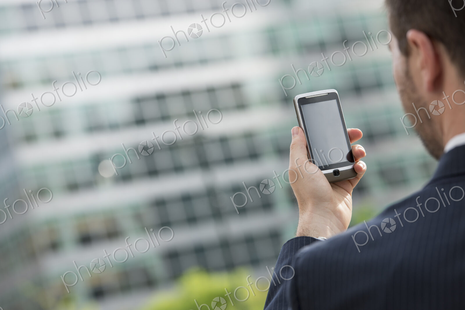 City life. People on the move. A man in a business suit checking his messages on his…