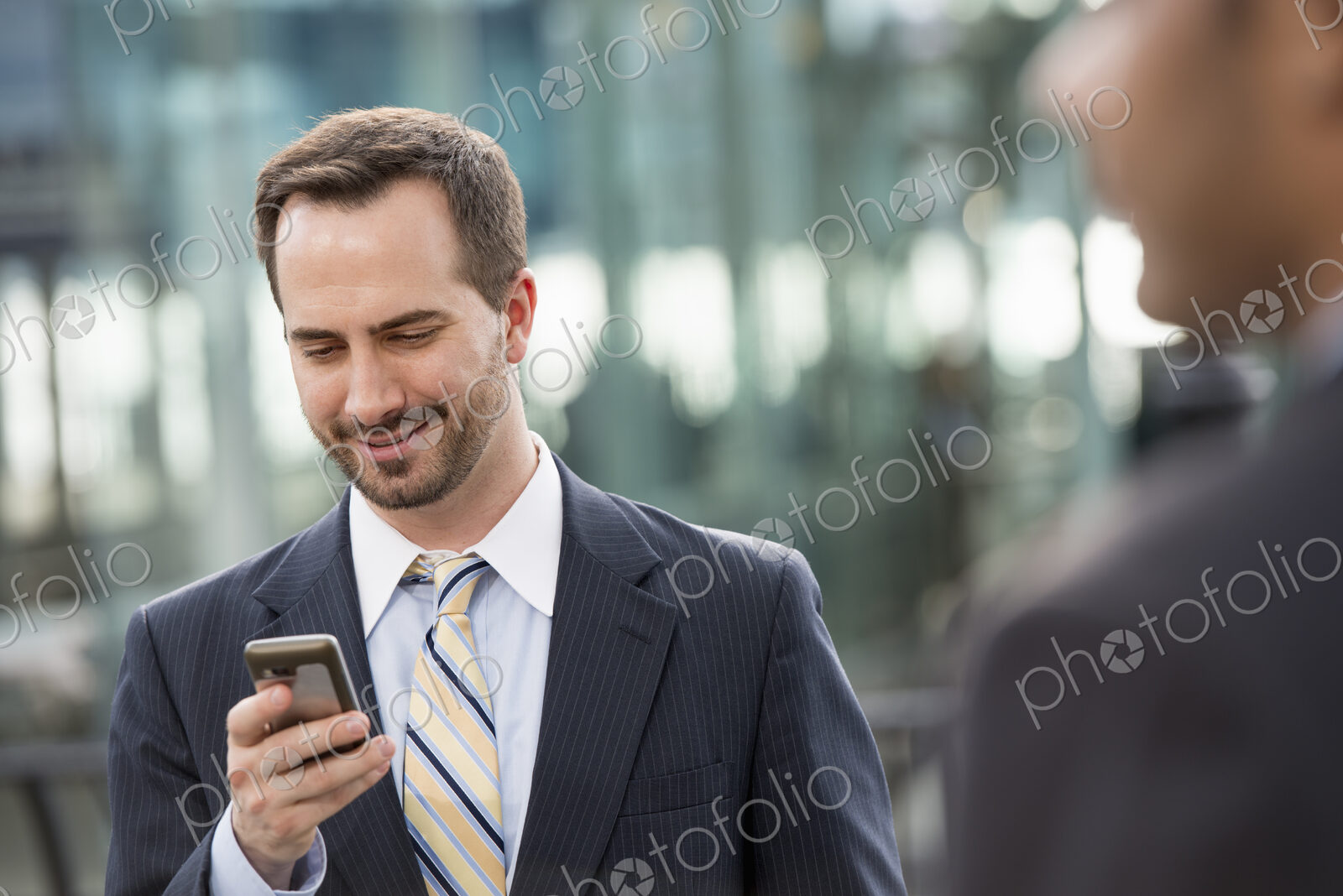 City life. People on the move. A man in a business suit checking his messages on his…