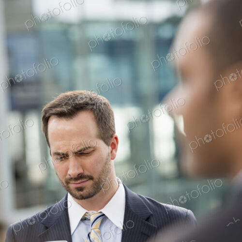 City life. People on the move. A man in a business suit checking his messages on his… City life. People on the move. A man in a business suit checking his messages on his…