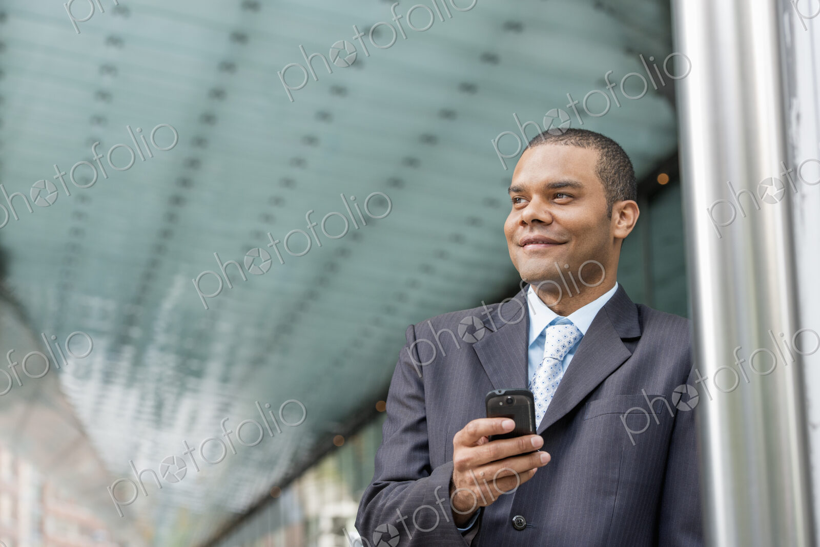 City life. People on the move. A man in a business suit checking his messages on his…