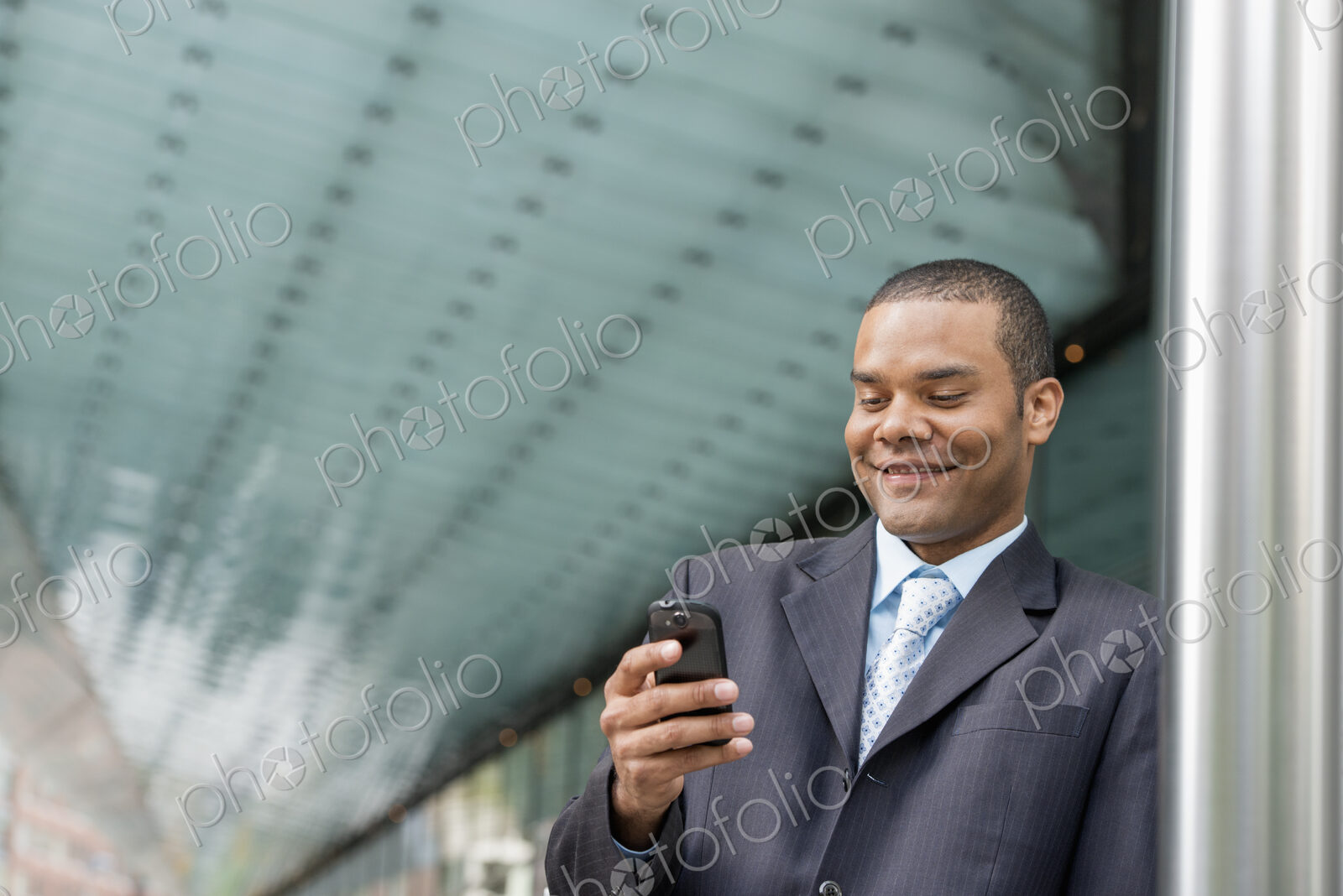 City life. People on the move. A man in a business suit checking his messages on his…