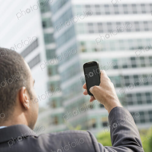 City life. People on the move. A man in a business suit holding his smart phone at… City life. People on the move. A man in a business suit holding his smart phone at…