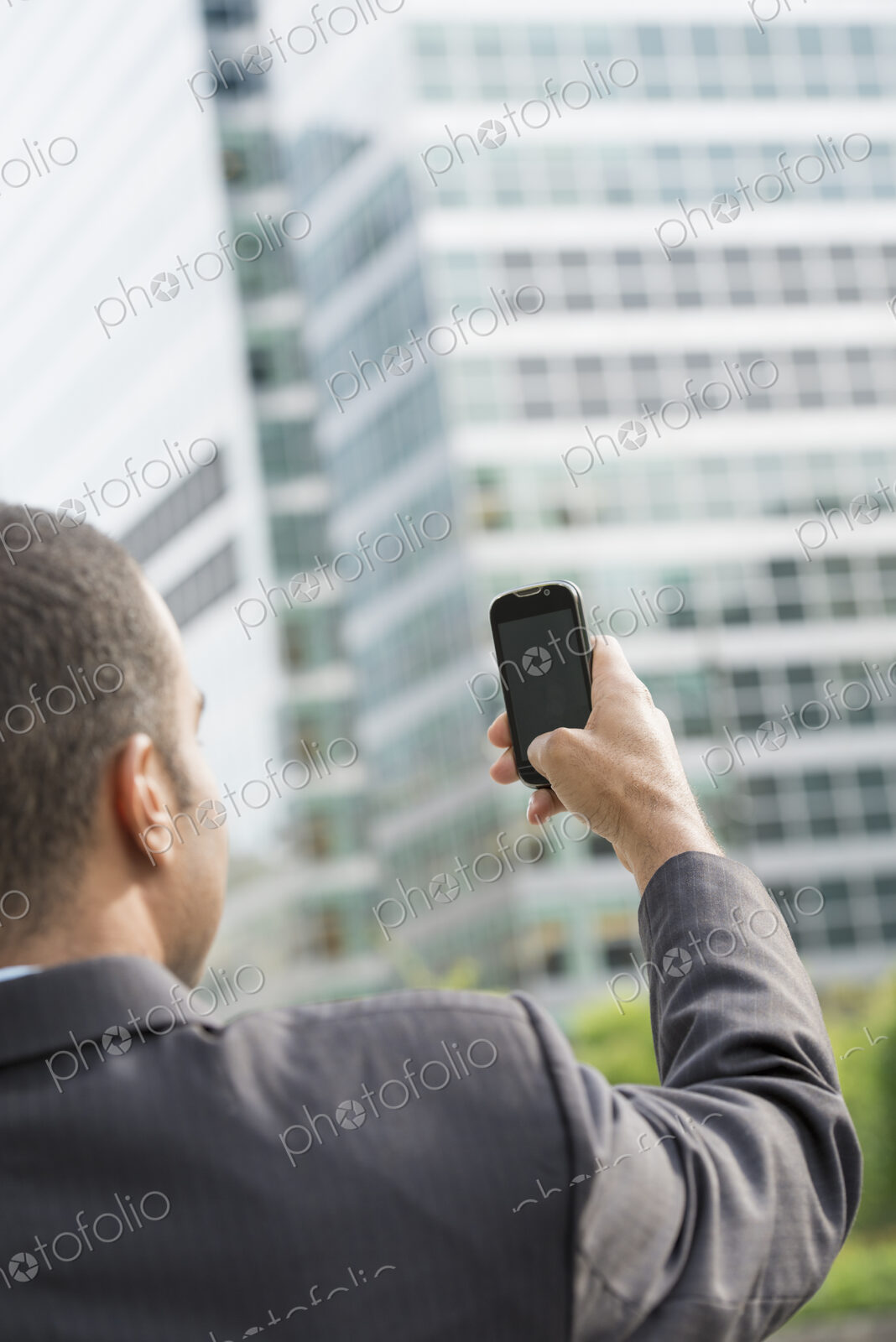 City life. People on the move. A man in a business suit holding his smart phone at…
