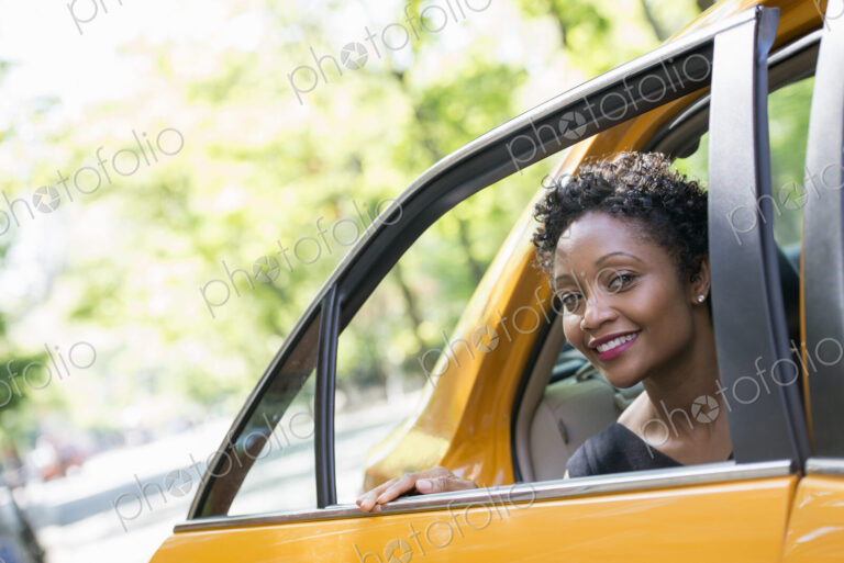 City life. People on the move. A woman getting out of the rear passenger seat of a…