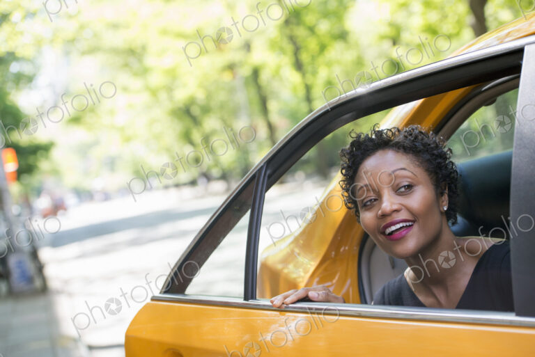 City life. People on the move. A woman getting out of the rear passenger seat of a…
