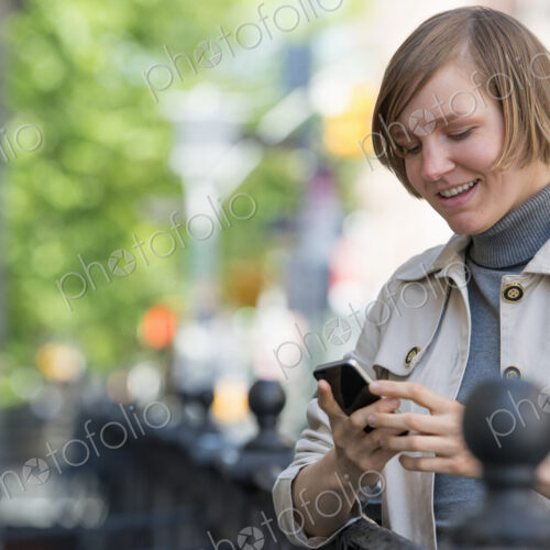 City life. People on the move. A woman in a jacket checking her smart phone. City life. People on the move. A woman in a jacket checking her smart phone.