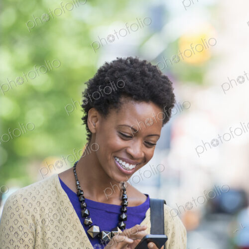 City life. People on the move. A woman in a purple dress checking her smart phone. City life. People on the move. A woman in a purple dress checking her smart phone.