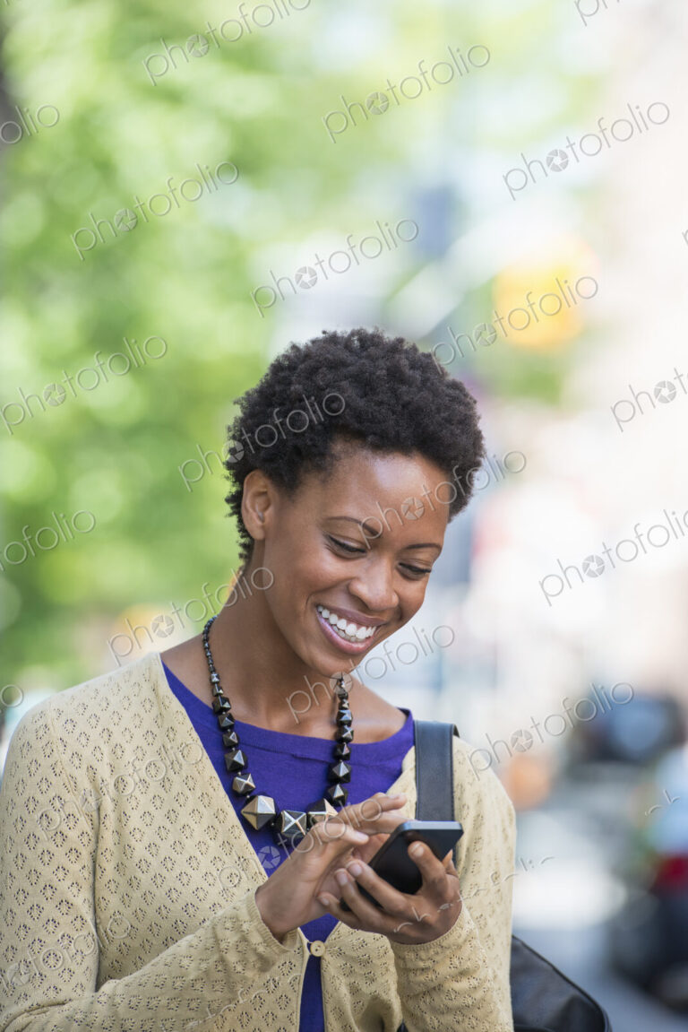 City life. People on the move. A woman in a purple dress checking her smart phone.
