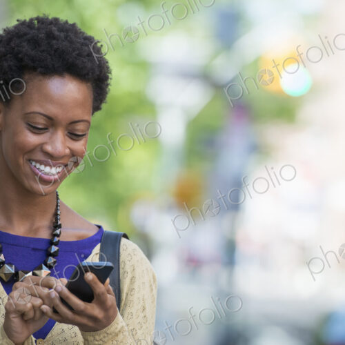 City life. People on the move. A woman in a purple dress checking her smart phone. City life. People on the move. A woman in a purple dress checking her smart phone.