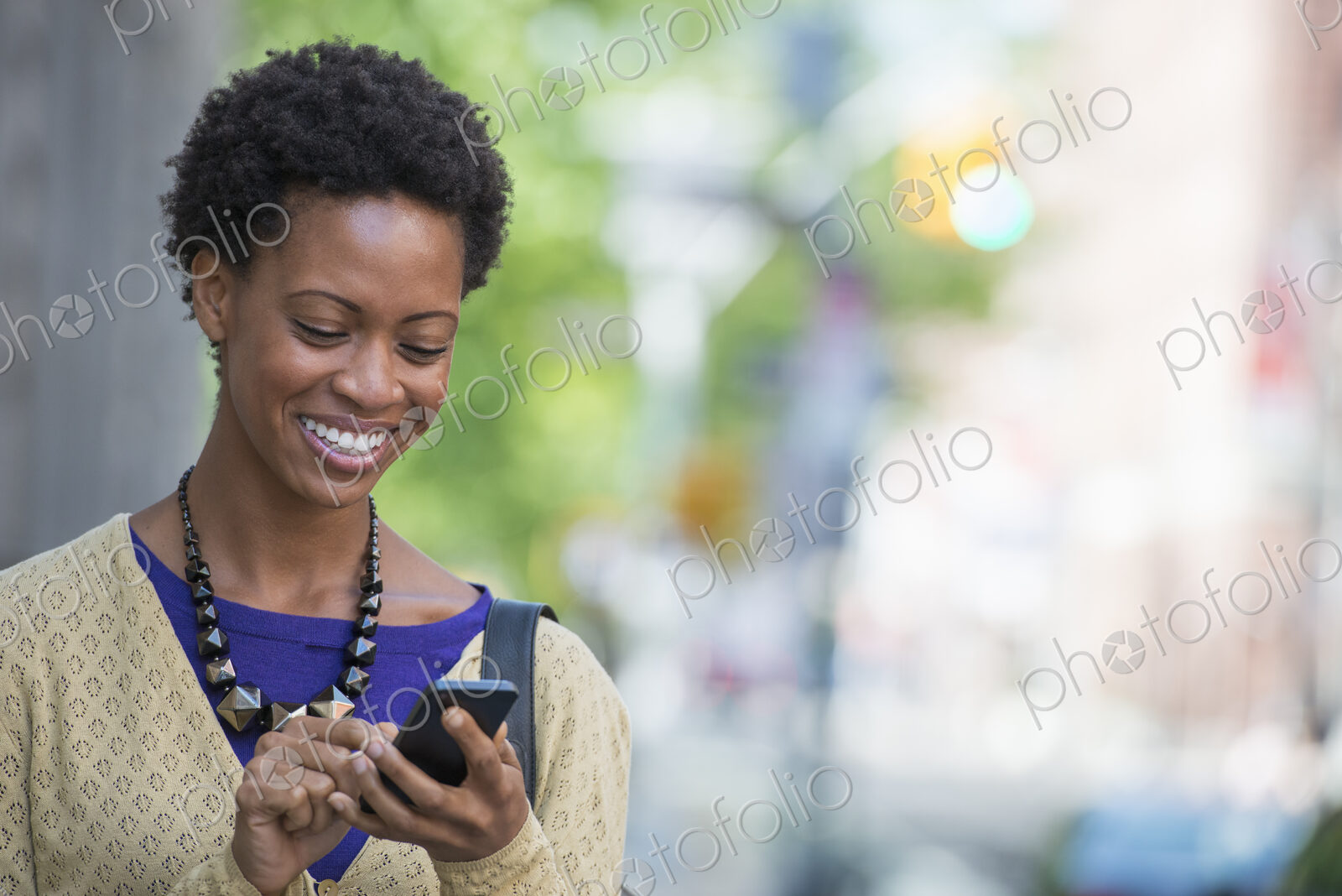 City life. People on the move. A woman in a purple dress checking her smart phone.