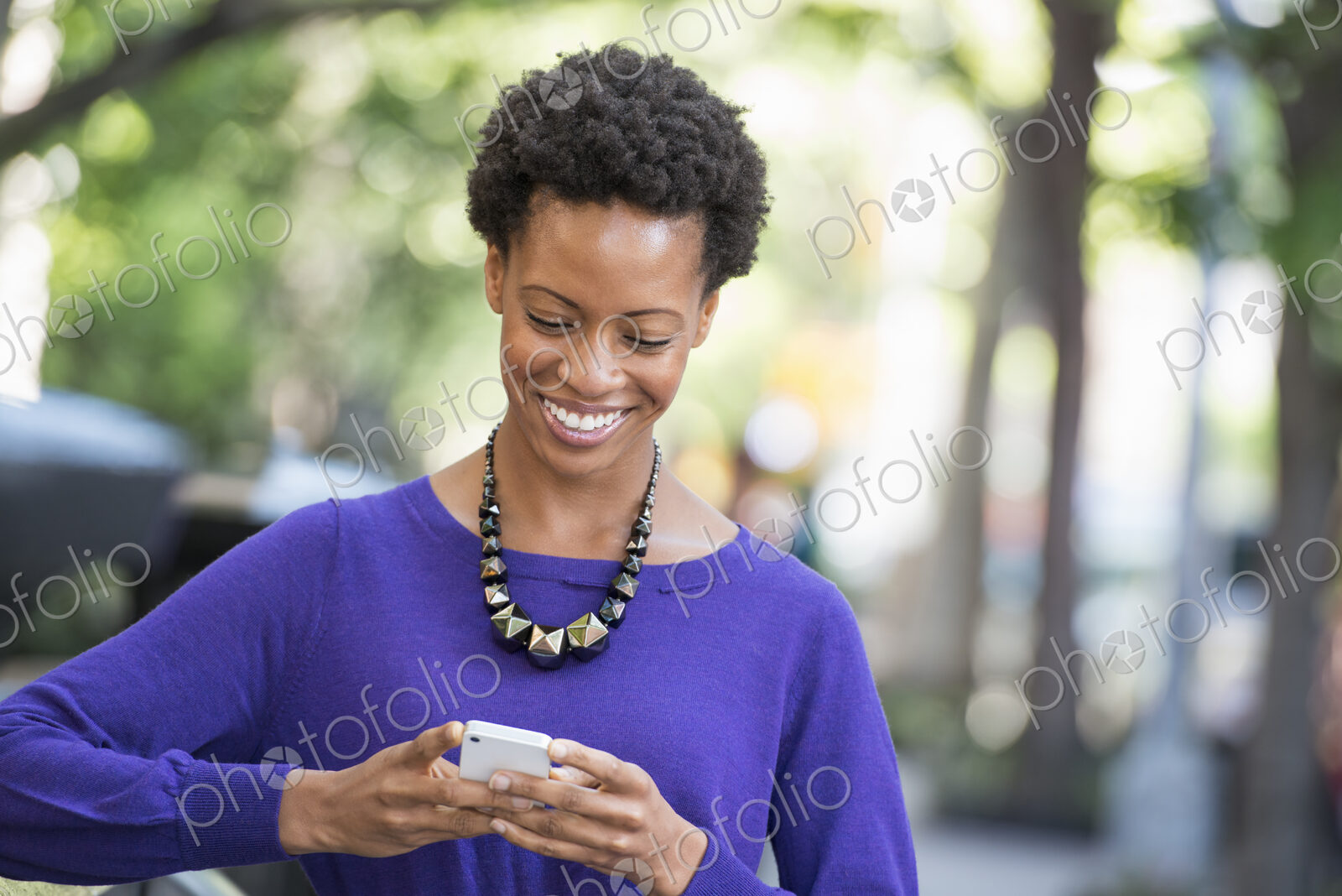 City life. People on the move. A woman in a purple dress checking her smart phone.