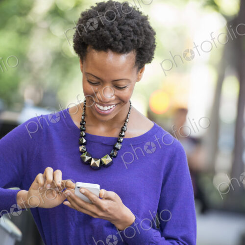 City life. People on the move. A woman in a purple dress checking her smart phone. City life. People on the move. A woman in a purple dress checking her smart phone.