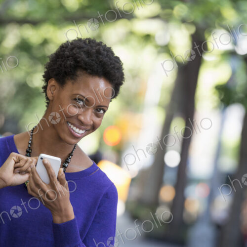 City life. People on the move. A woman in a purple dress checking her smart phone. City life. People on the move. A woman in a purple dress checking her smart phone.