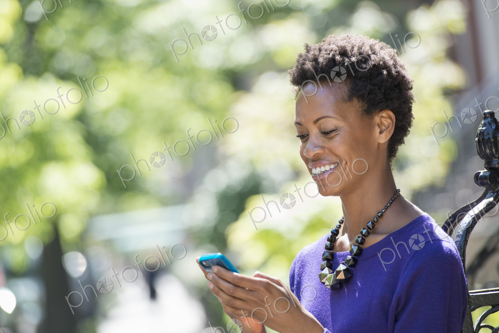 City life. People on the move. A woman in a purple dress checking her smart phone.