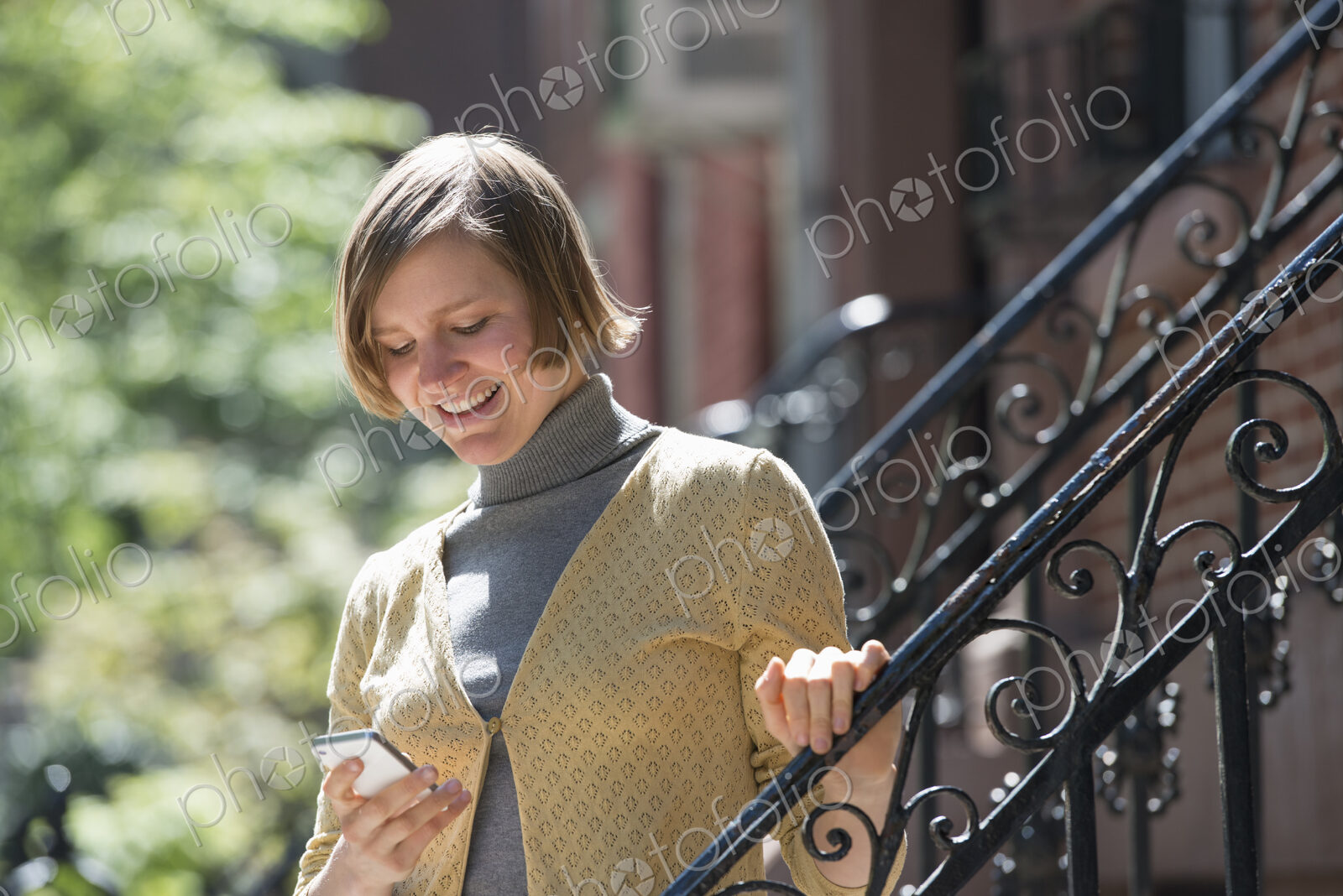 City life. People on the move. A woman on steps outside a townhouse, checking her…