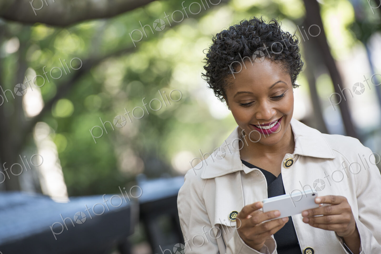 City life. People on the move. A woman outdoors in the park, checking her smart phone.