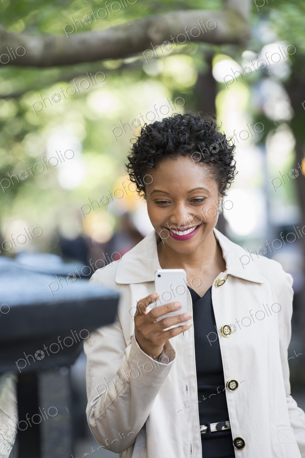 City life. People on the move. A woman outdoors in the park, checking her smart phone.