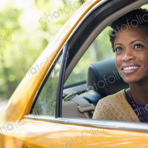 City life. People on the move. A woman sitting in the rear passenger seat of a yellow cab. City life. People on the move. A woman sitting in the rear passenger seat of a yellow cab.