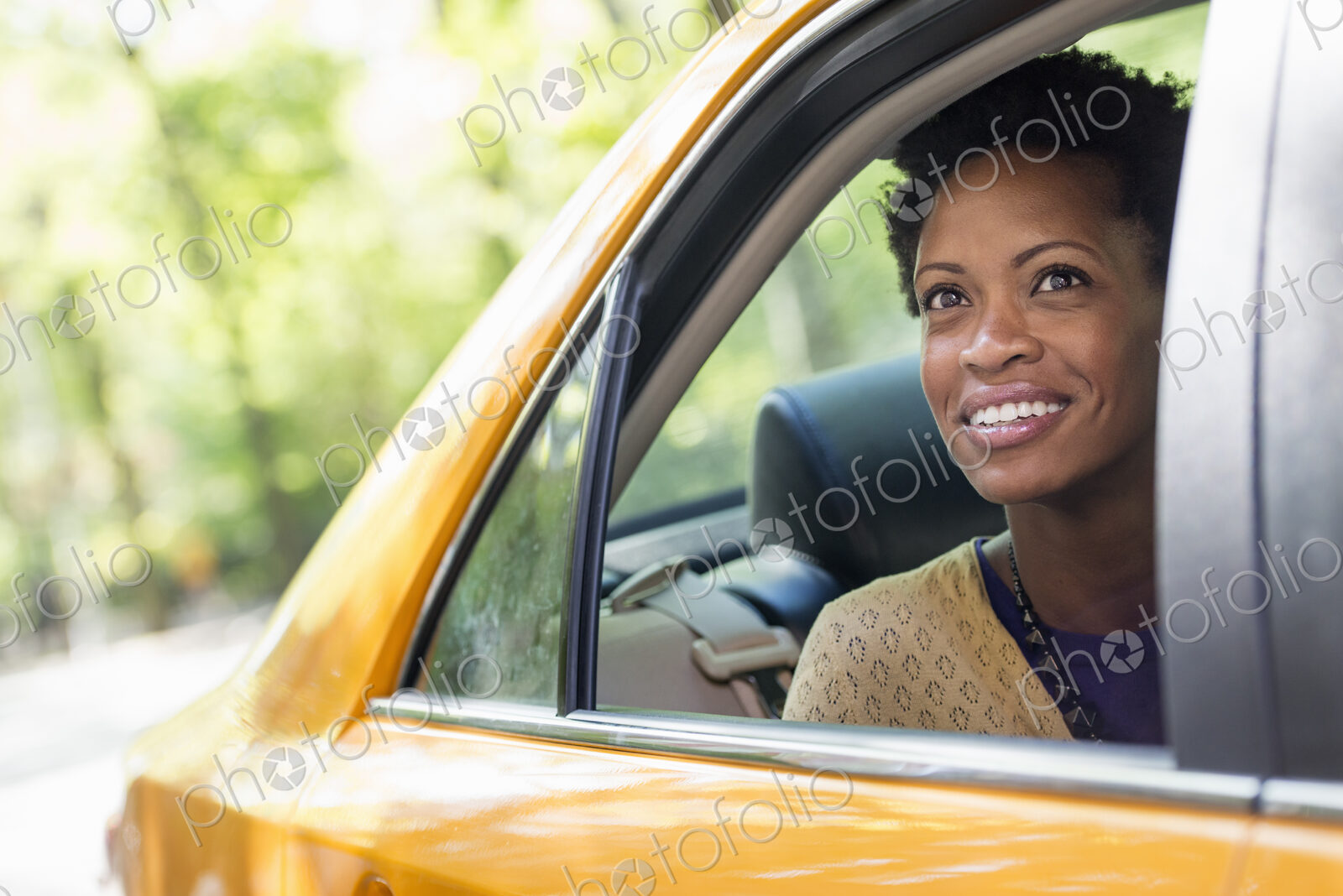 City life. People on the move. A woman sitting in the rear passenger seat of a yellow cab.