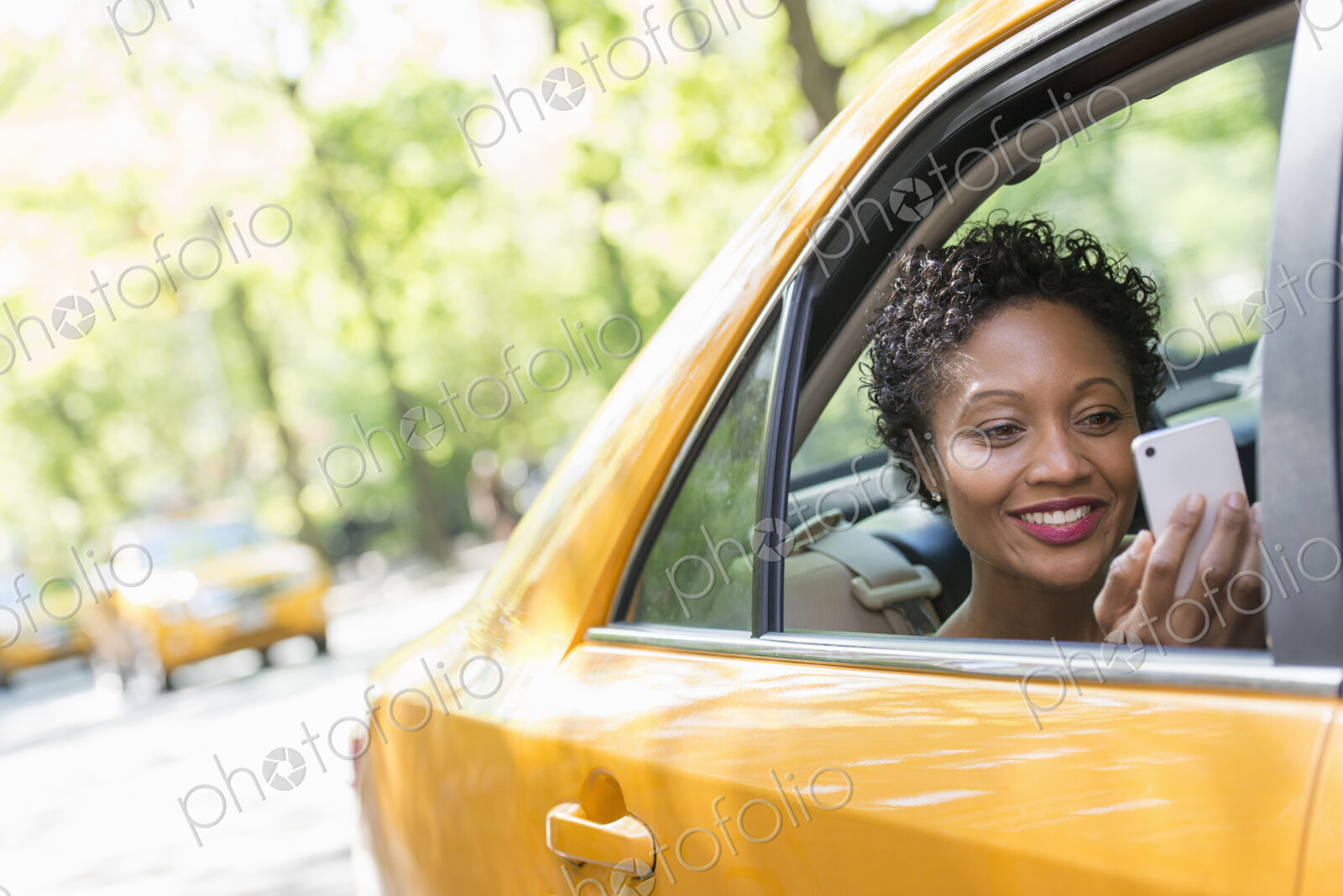 City life. People on the move. A woman sitting in the rear passenger seat of a yellow…