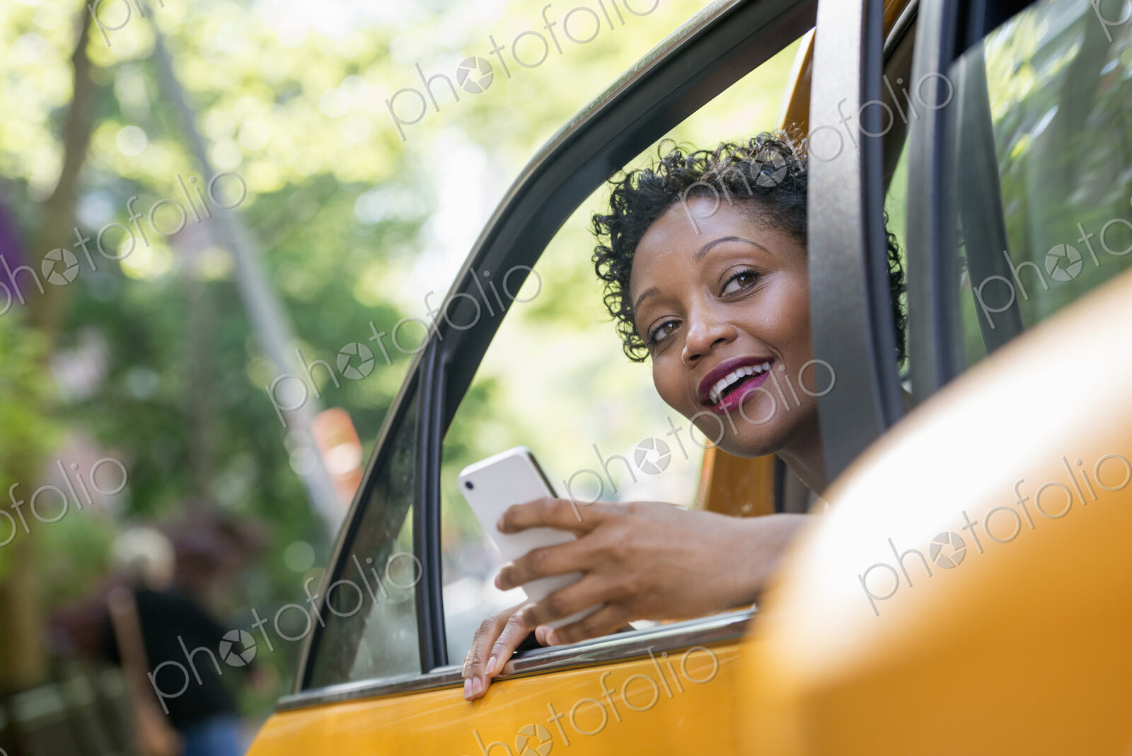 City life. People on the move. A woman sitting in the rear passenger seat of a yellow…
