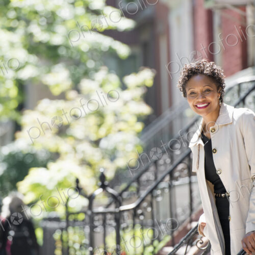 City life. People on the move. A woman walking down steps outside a town house. City life. People on the move. A woman walking down steps outside a town house.
