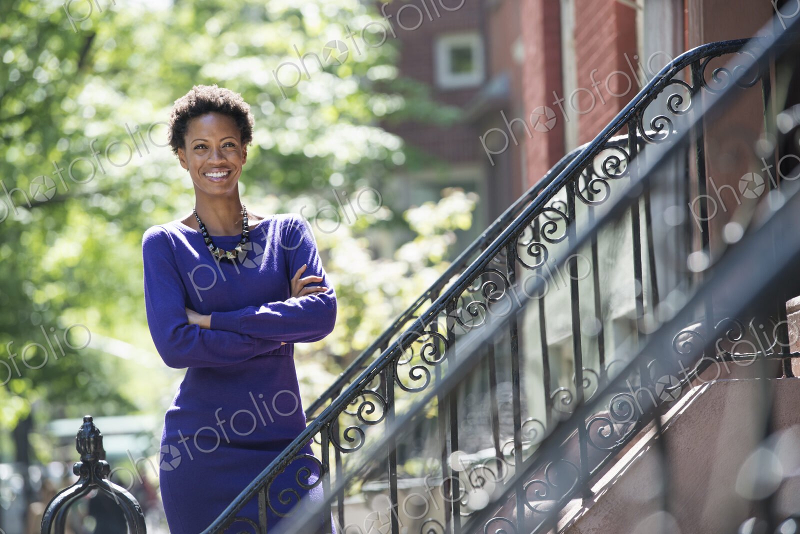 City life. People on the move. A woman wearing a purple dress, standing on the steps…