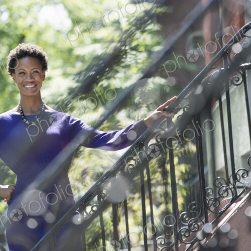 City life. People on the move. A woman wearing a purple dress, standing on the steps…