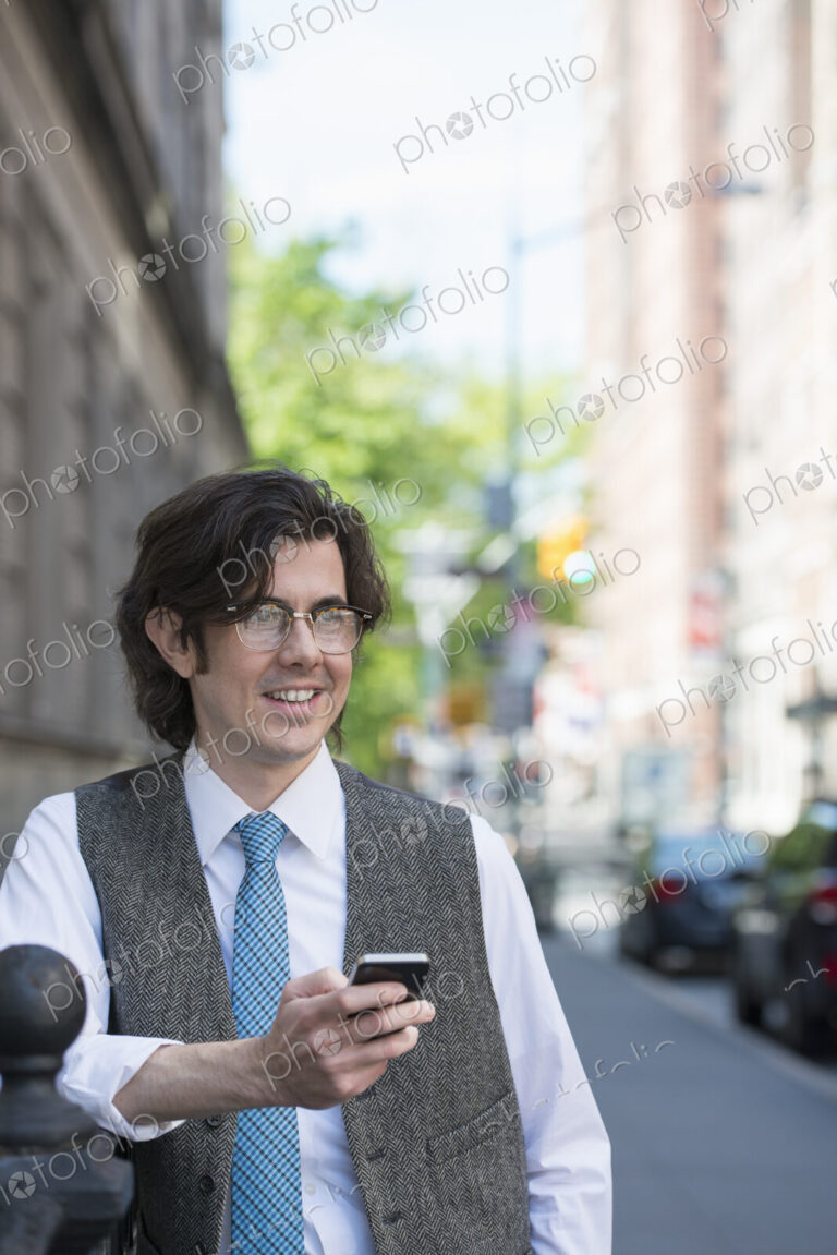 City life. People on the move. A young business man on the street checking his smart…