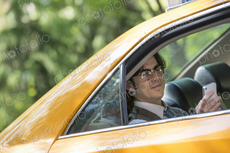 City life. People on the move. A young man in the back seat of a taxi.