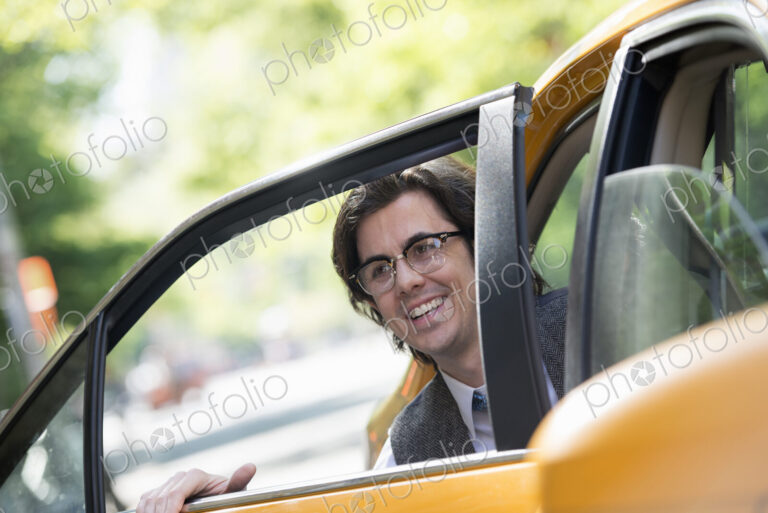 City life. People on the move. A young man in the back seat of a taxi.
