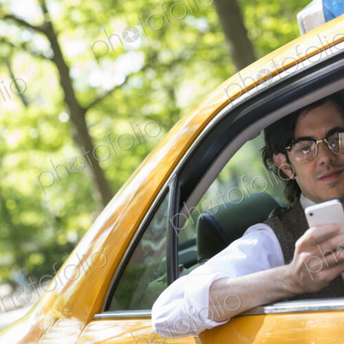 City life. People on the move. A young man in the back seat of a yellow cab, looking… City life. People on the move. A young man in the back seat of a yellow cab, looking…