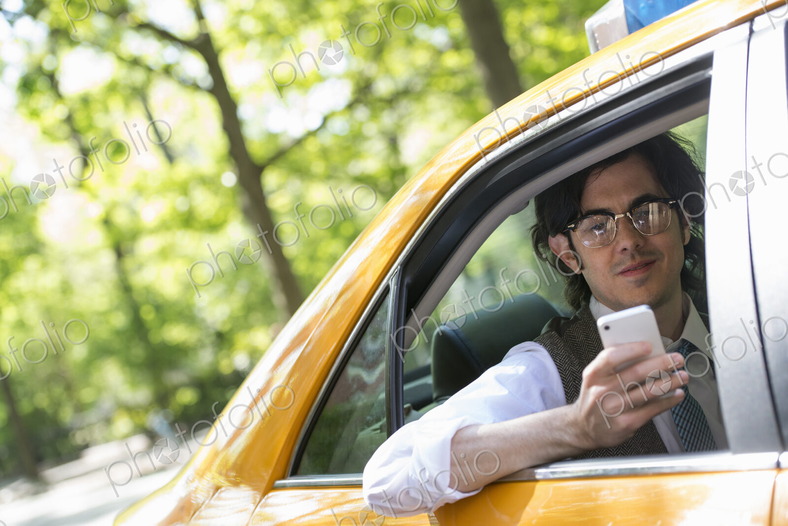 City life. People on the move. A young man in the back seat of a yellow cab, looking…