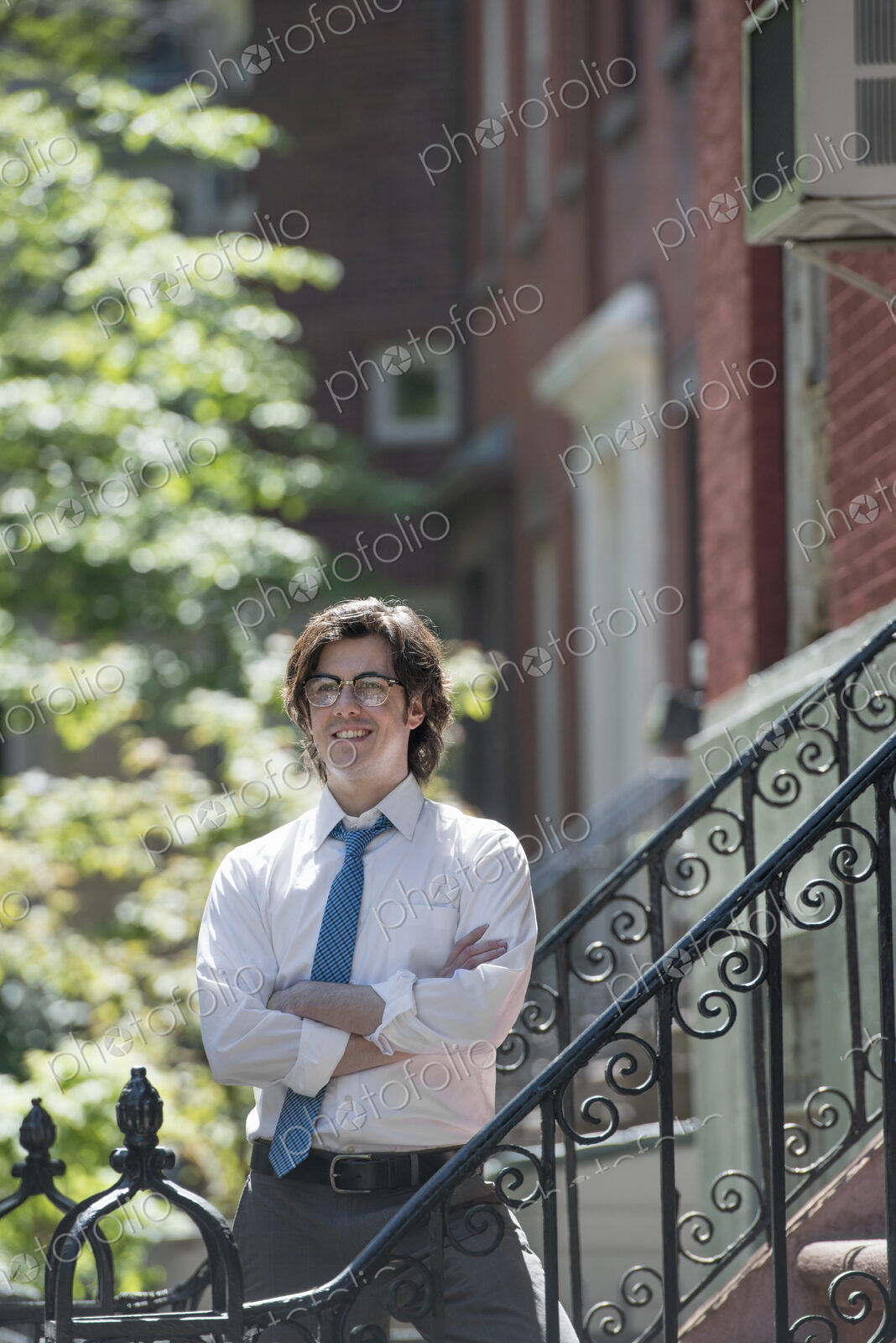 City life. People on the move. A young man in w white shirt and blue tie, standing…