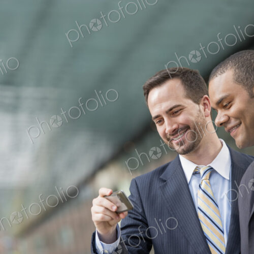 City life. People on the move. Two men in business suits, looking at a smart phone,… City life. People on the move. Two men in business suits, looking at a smart phone,…
