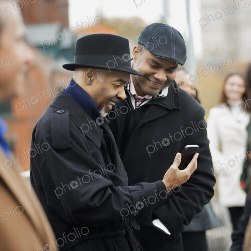 City life. Two men standing side by side, keeping in contact, using mobile phones, and… City life. Two men standing side by side, keeping in contact, using mobile phones, and…