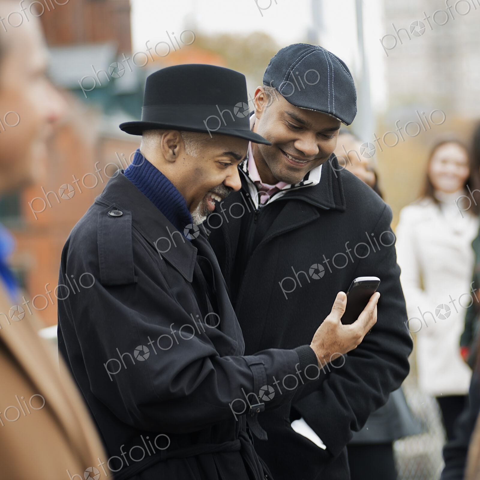 City life. Two men standing side by side, keeping in contact, using mobile phones, and…