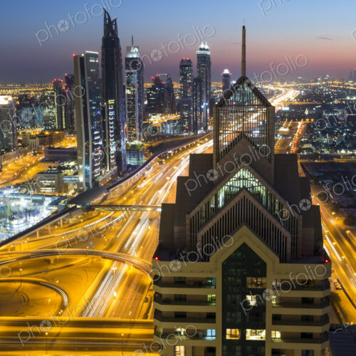 Cityscape with illuminated skyscrapers and light trails on highways at dusk. Cityscape with illuminated skyscrapers and light trails on highways at dusk.