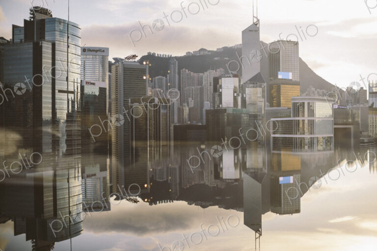 Cityscape with modern skyscrapers reflected in calm sea.